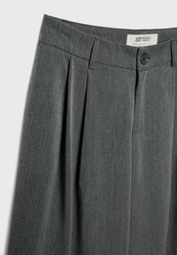 Grau gefaltete Hosen mit glatter Textur, ausgestattet mit einem Knopfverschluss am Bund und einem dezenten Stoffmuster.