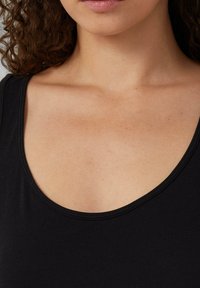Zwarte tanktop met een ronde hals, gemaakt van zacht materiaal, met een gladde textuur en minimale stiksels langs de randen.