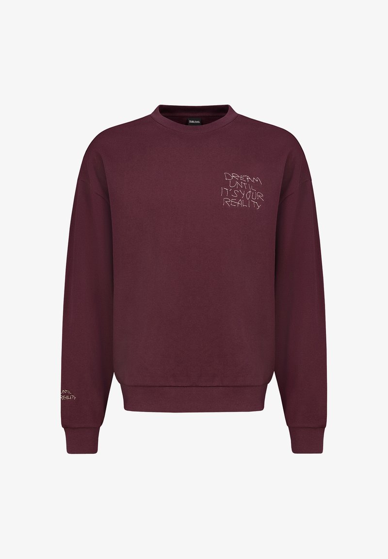 Bordeaux sweatshirt met een ribgebreide ronde hals en lange mouwen. Heeft witte geborduurde tekst op de voorkant en de linker mouw.