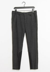 Grå skräddarsydda byxor med en mjuk textur, två sidfickor och svarta detaljer längst ner. Kontraststygn på sidorna är synliga.