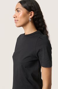 Tricou negru cu mânecă scurtă, fabricat din bumbac moale, cu decolteu la baza gâtului și croială ajustată, fără modele sau ornamente suplimentare.