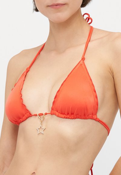 Woman wearing an orange triangle bikini top with thin straps tied around neck and back, featuring a small gold star charm hanging in the center.