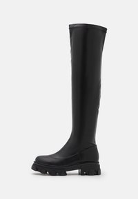 Knee-high black vegan leather boots with a chunky sole, smooth texture, rounded toe, and minimal stitching details on a white background.