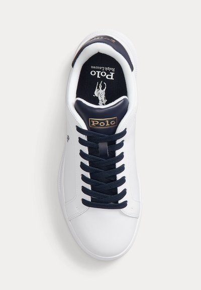 Baskets blanches avec lacets bleu marine, languette rembourrée bleu marine avec étiquette dorée « Polo » et semelle intérieure noire avec logo Polo Ralph Lauren.