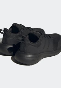 Svarta träningsskor med meshtov, vadderad krage, strukturerad sula och tre ränder på sidan.