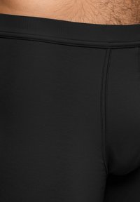 Pantaloni de baie negri dintr-un material neted și elastic. Prezintă o culoare uniformă, un tiv elastic la talie și cusături plate pentru confort.