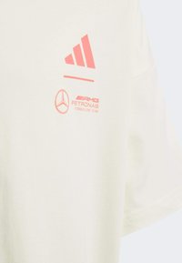 Cremefarvet bomulds T-shirt med pink trykte logoer: Adidas tre striber og Mercedes AMG Petronas Formula One Team. Korte ærmer.