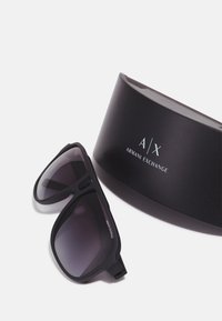 Ochelari de soare negri cu lentile în degradé, având un finisaj mate, însoțiți de un toc dur negru, cu un logo argintiu "A/X Armani Exchange".