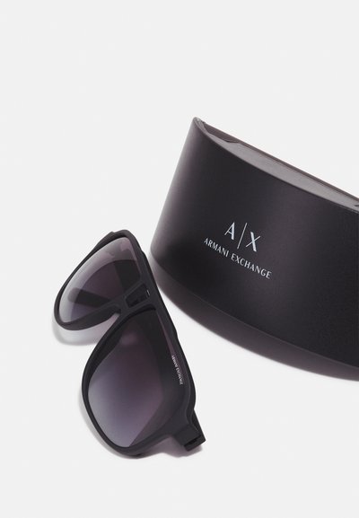 Lunettes de soleil noires avec verres dégradés, en finition mate, accompagnées d'un étui rigide noir arborant un logo argenté "A/X Armani Exchange".