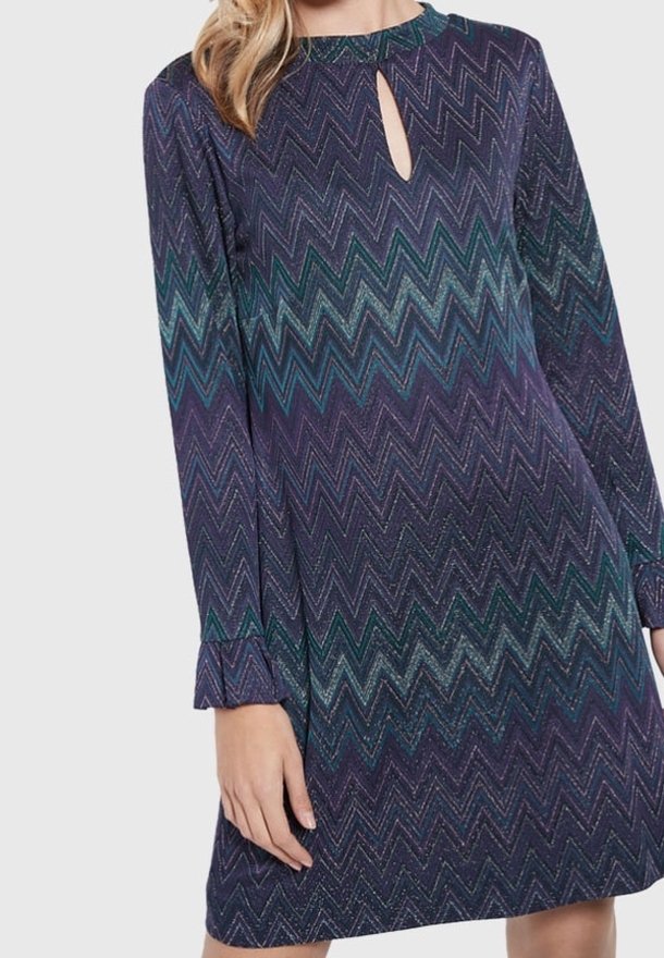 Abito a maniche lunghe di colore viola con un motivo a zig-zag in teal e blu. Presenta un colletto a chiave e polsini a balze.