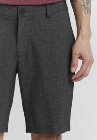 Gray fabric shorts with a textured finish, featuring a front button closure, belt loops, and side pockets. The hem reaches above the knee.
