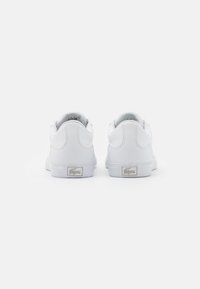 Vita sneakers med övre del i slätt läder, rundad tå och platt gummisula. Har accentuerad logotyp på hälen och vadderad krage.