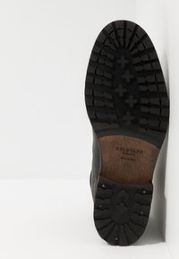 Semelle extérieure en caoutchouc noir avec motif de bande de roulement texturé. Accent en bois au talon avec branding embossé. Tige en cuir au design structuré.