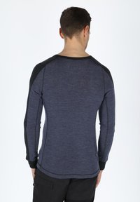 Navy long-sleeve shirt with contrasting black raglan sleeves, textured fabric, and side stitching details. Back view with a rounded neckline.
