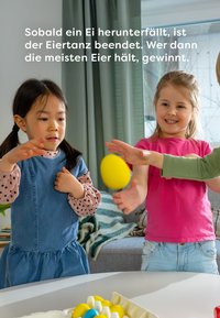 Two children in a bright room play with yellow plastic eggs. One child wears a denim dress with a polka dot shirt, the other in a pink shirt.