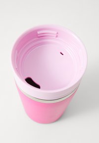 Rosa reisekrus med lys rosa lokk, som har et drikkespout og et lite ventilasjons hull, på en hvit bakgrunn.