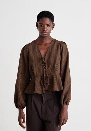 Brown striped peplum blouse with a deep v-neck, tie closure, and loose long sleeves. The fabric appears textured and lightweight.