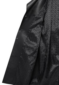 Zwarte leren jas met een gestructureerde buitenlaag. De voering is van zwart fabric met cirkelpatronen. Twee knopen zichtbaar aan de voorkant.
