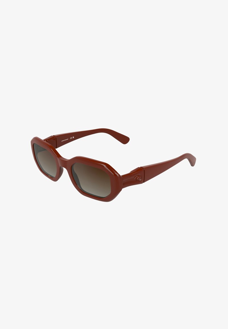 Lunettes de soleil en plastique marron avec un design géométrique, verres teintés dégradés foncés, monture épaisse et branches élégamment courbées.