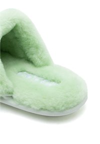 Μαλακή πράσινη φλις παντόφλα εσωτερικού χώρου με παχιά εσωτερική επένδυση και λευκή σόλα, σχεδιασμένη για άνεση και ζεστασιά.