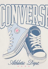Kaks Converse'i jalanõud on illustreeritud: üks kõrge sinine ja teine madal tumesinine. Omadusteks on valged kingapaelad ja logo kleebised.