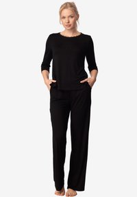 Czarny zestaw odzieży domowej z okrągłym dekoltem, rękawami 3/4 oraz prostymi spodniami z bocznymi kieszeniami. Miękka, gładka tekstura materiału.