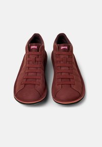 Röda mockasneakers med en låg profil, med sex matchande snörningar och en texturerad gummisula. "Camper"-logotyp på tungan.