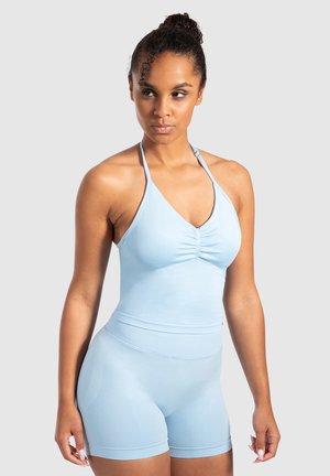 Top de entrenamiento azul claro con estilo halter y fruncidos, acompañado de pantalones cortos de cintura alta a juego, ambos hechos de una tela elástica y suave.