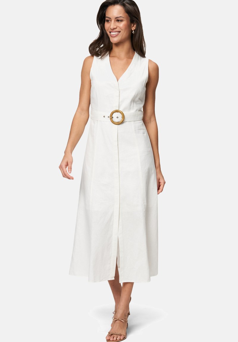 Robe maxi blanche sans manches avec un décolleté en V, des boutons à l'avant et une taille cintrée mettant en valeur une ceinture ronde couleur beige. Texture lisse, fente à mi-cuisse.