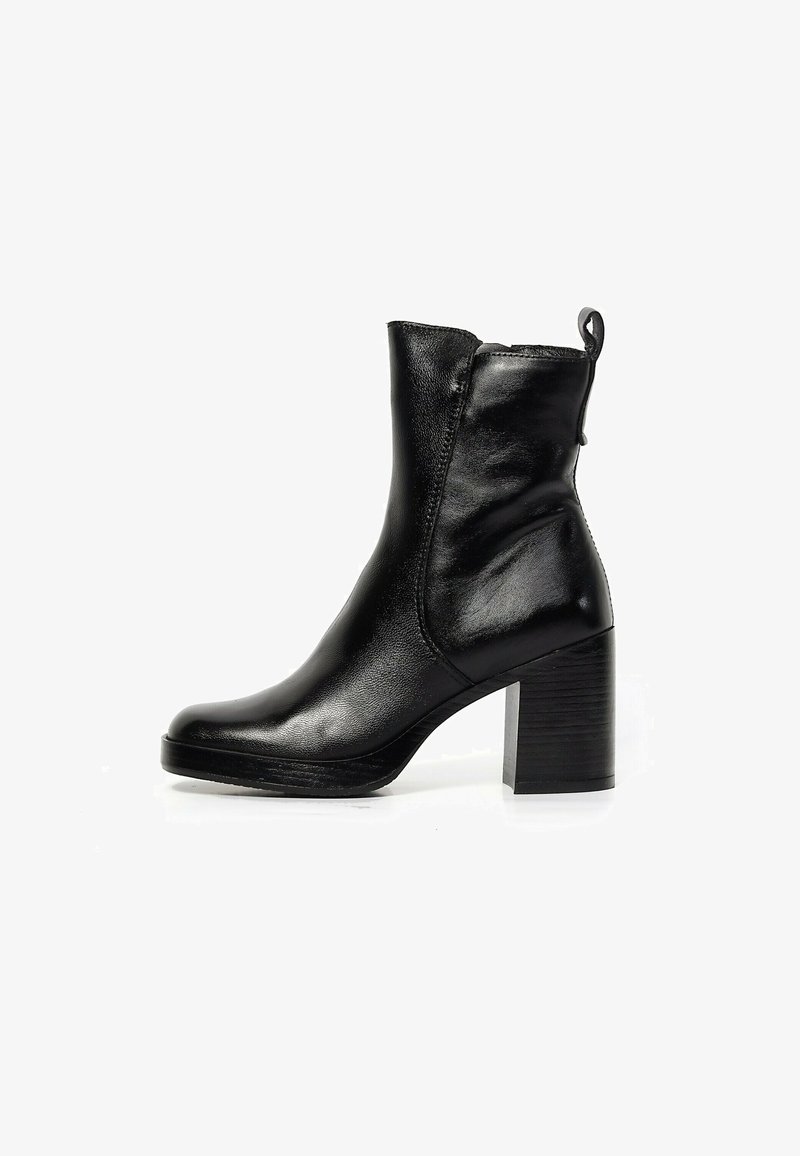 Bottine noire en cuir avec talon bloc, bout arrondi et languette à l’arrière présentée sur fond blanc.