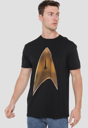 Black t-shirt with a large, shiny gold Starfleet insignia graphic on the front, featuring a pointed design and a central star detail.