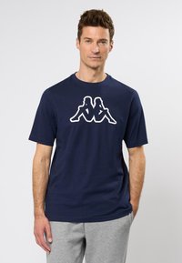 Tengerészkék pamut póló, fehér Kappa logó grafikával. Rövid ujjak és kerek nyakú design biztosítja a laza illeszkedést. Minimalista stílus.