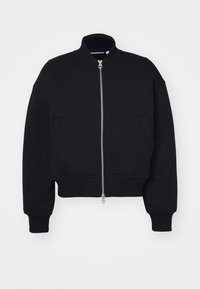 Veste bomber noire raccourcie en tissu doux, avec un col montant, une fermeture éclair sur le devant et des poches latérales. Design simple avec des poignets côtelés.