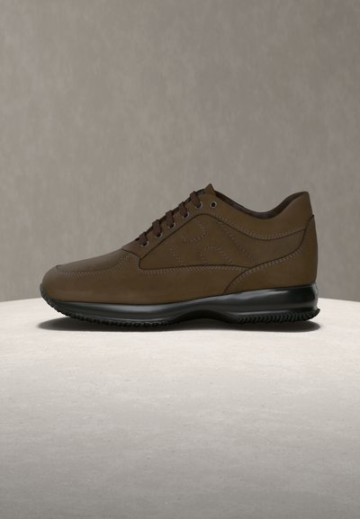 Καφέ δερμάτινο αθλητικό παπούτσι με ομαλή υφή, στρογγυλεμένη μύτη και μαύρη ελαστική σόλα. Διαθέτει μπροστινή δέση κορδονιών και διακριτικές λεπτομέρειες ραφών.