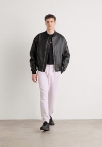 Sort læderbomberjakke, sort t-shirt, lyserøde sweatpants og sorte sneakers. Enkel design med elastiske manchetter og lynlås.