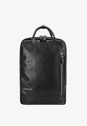 Musta reppu, joka on valmistettu teksturoituneesta nahasta, jossa on kaksinkertaiset kahvat, sivun vetoketjutasku ja timantin muotoinen brändilogo alareunassa.