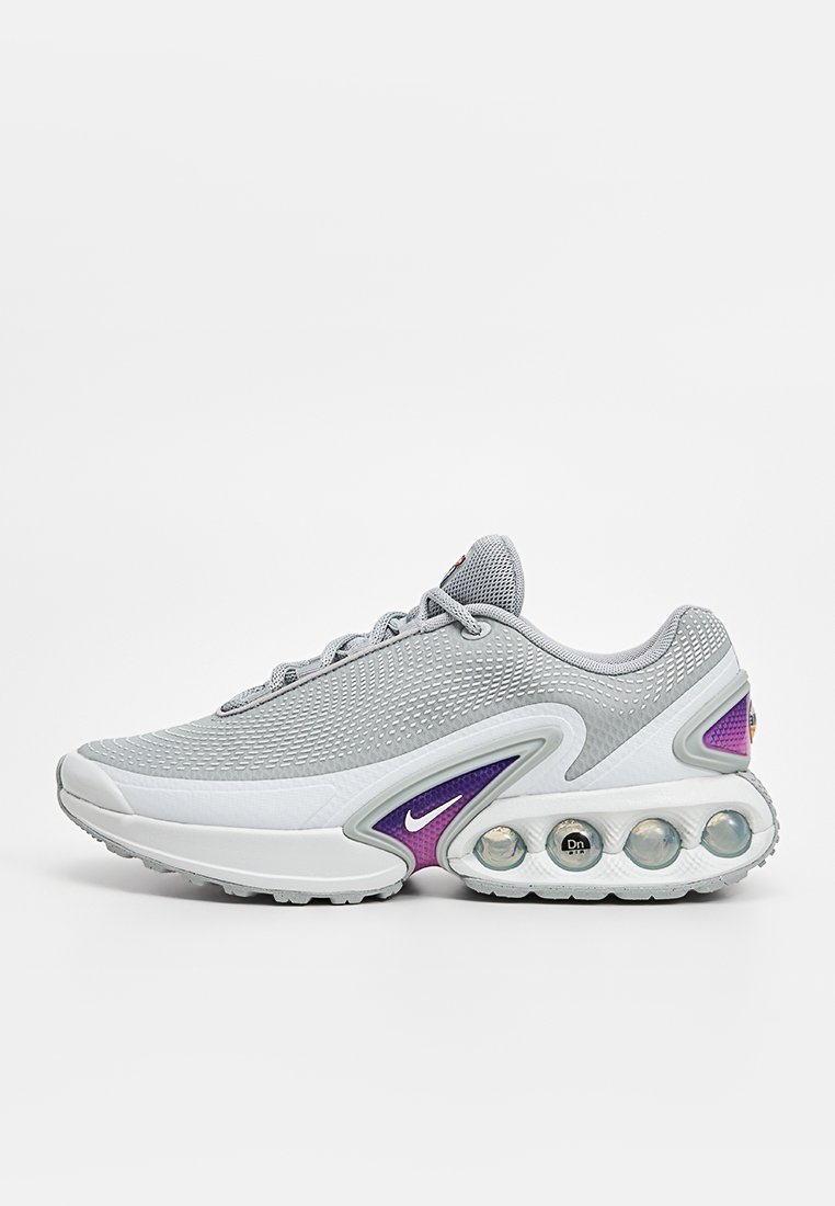 Baskets en maille grises avec un dessus texturé, accents violets et une semelle épaisse comportant des bulles de cushion d'air visibles. Logo Nike sur le côté.