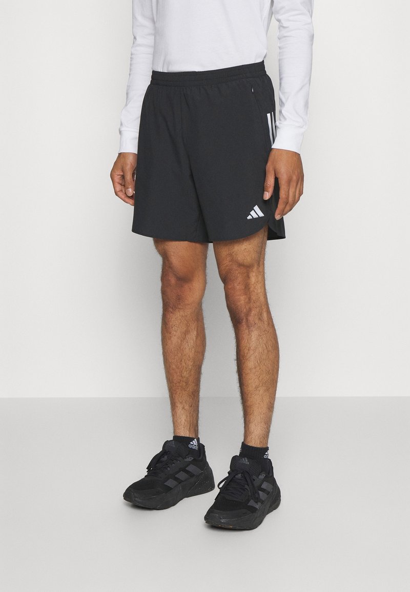 Shorts de sport noirs avec une taille élastique et des poches latérales. Présente trois rayures blanches et un logo Adidas sur la jambe gauche.