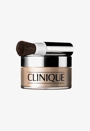 Clinique poeder in een heldere glazen pot met een beige tint. Voorzien van een zilveren deksel en een zwarte borstel voor applicatie die eraan is bevestigd.