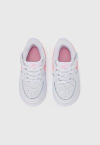 Sneakers bianchi con accenti rosa, tomaia in pelle liscia, punta perforata, lacci rotondi e linguetta e colletto imbottiti. Brand Nike visibile.