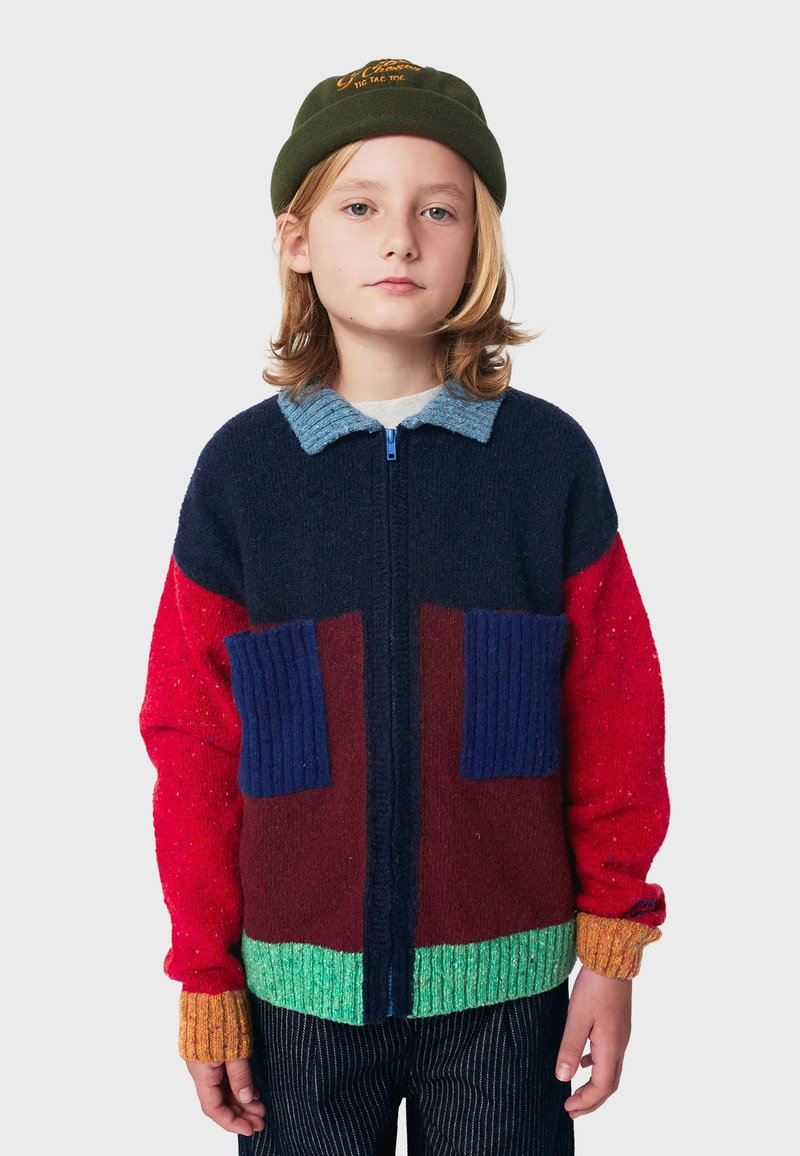 Mehrfarbiger Reißverschluss-Pullover mit Abschnitten in Marineblau, Rot, Burgunder und Grün; gerippte Bündchen; zwei blaue aufgenähte Taschen; strukturierter Strickstoff.