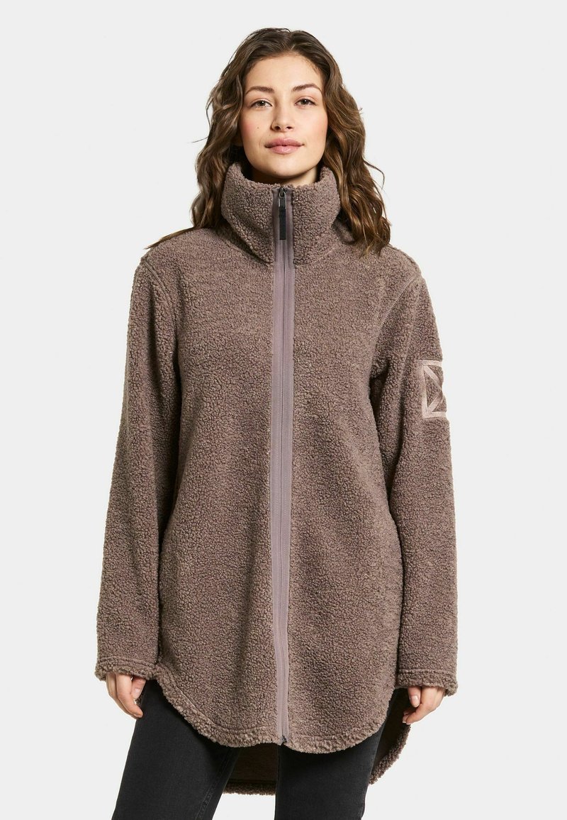 Bruine fleece jas met hoge kraag, volledige ritssluiting en lange mouwen. Kenmerkend zijn de gestructureerde stof en de zijnaadzakken.