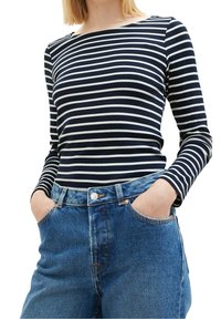 Navy- und weiß gestreiftes Langarmoberteil mit einem Bootsausschnitt, kombiniert mit hochtaillierten blauen Denim-Jeans mit Fronttaschen.