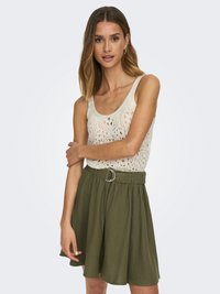 Débardeur crème en tricot avec trame aérée ; jupe verte évasée avec une ceinture en tissu et boucle en argent ; coupe décontractée ; longueur genoux.