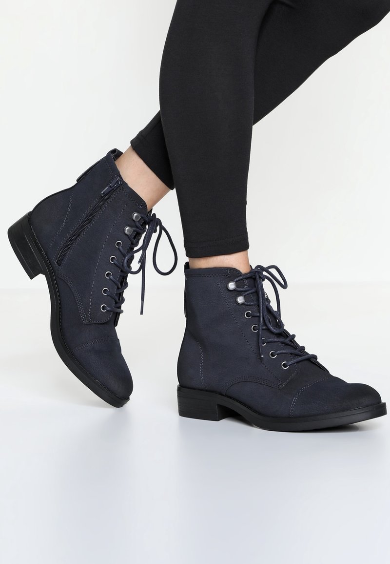 Mörkblå ankle boots i texturerat tyg, med snabbsnörning fram, sidodragkedja och en liten klack.
