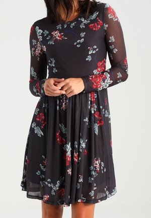 Zwarte bloemenjurk met lange doorschijnende mouwen, voorzien van rode en blauwe bloemenpatronen en een nauwsluitend lijfje, uitlopend in een uitlopende rok.