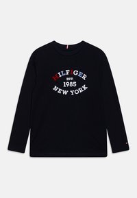 T-shirt a maniche lunghe nera in cotone, con una grafica testuale bianca, rossa e blu che recita "HILFIGER EST. 1985 NEW YORK."
