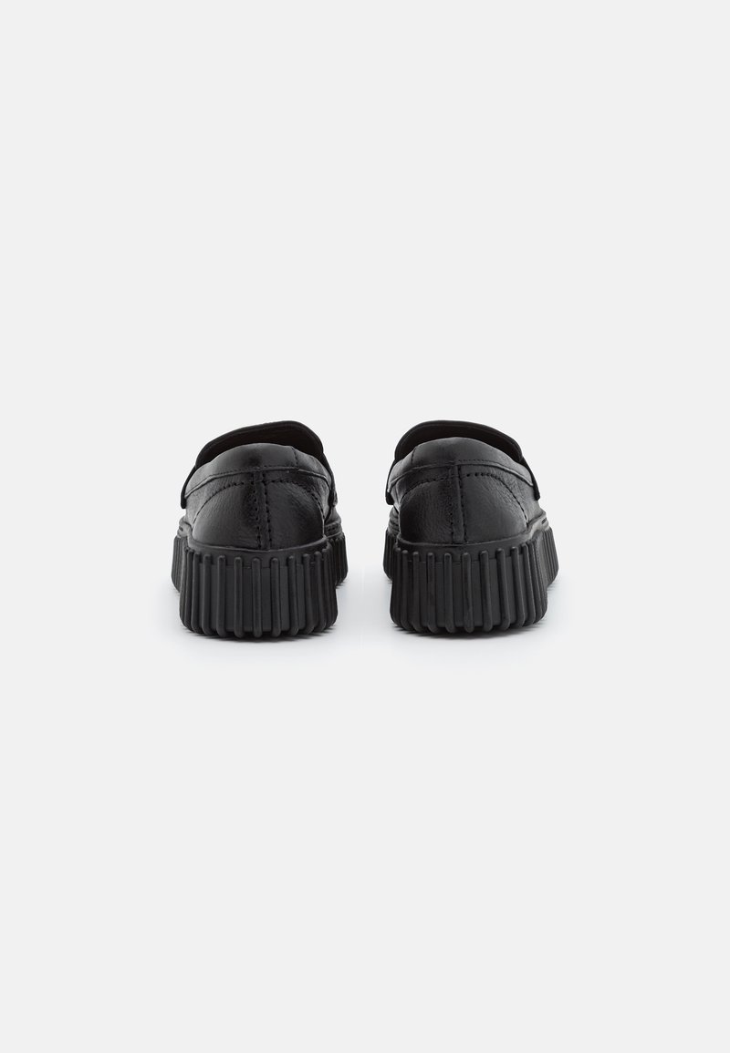 Chaussures en cuir noir à la forme arrondie, dotées d'une semelle en caoutchouc nervurée et d'un design lisse et minimaliste. Aucune motif ou accent visible.