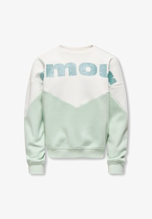 Heleroheline ja valge dressipluus geomeetrilise mustriga, millel on ees suured sädelevad sinised tähed ja soonikkoes varrukasäärised.