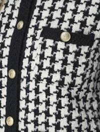 Blazer a fantasia houndstooth navy e bianco in tessuto testurizzato, con bottoni dorati e una piccola tasca sul lato sinistro.